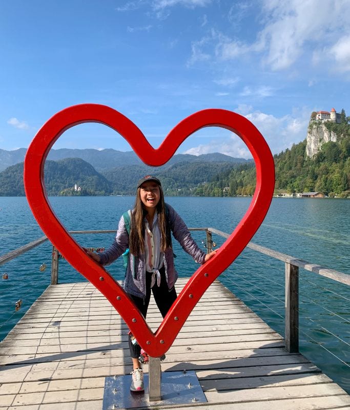 A picture of Kristin holding a heart art installation on the docks around Lake Bled.