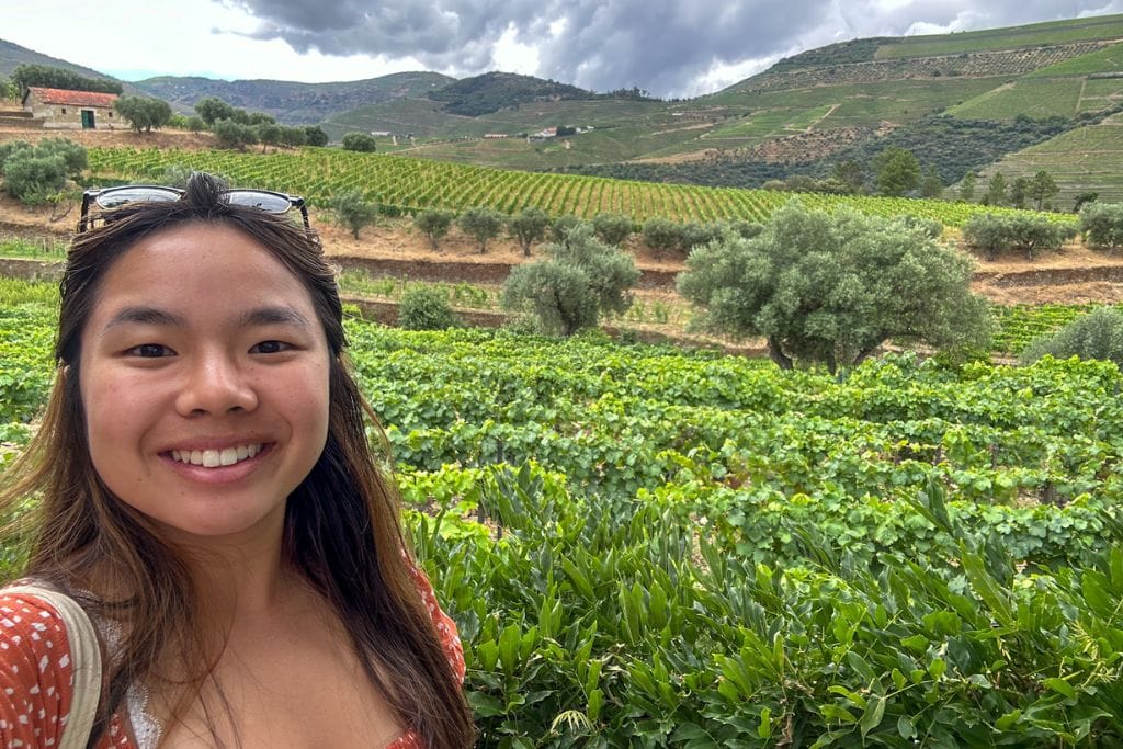 A picture of Kristin on a wine tasting tour with beautiful vineyards in the background.