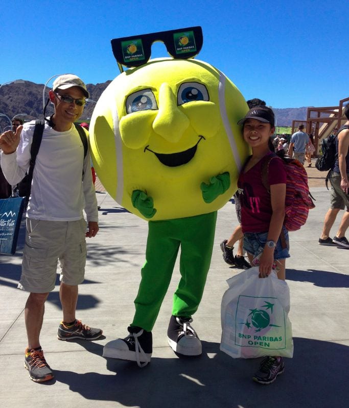 A picture of Kristin and her dad with a giant tennis ball mascot at the BNP Paribas Open.