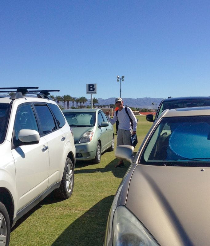 A picture of Kristin's dad standing next to their car in their awesome parking spot for the Indian wells tennis tournament parking lot.